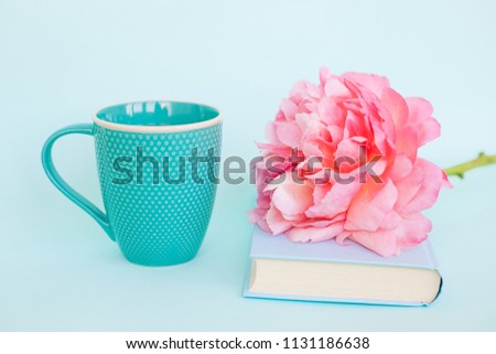 Peony flower and light blue book on blue background
