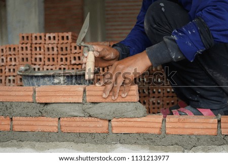 Bricklayer worker installing bricks on construction site.