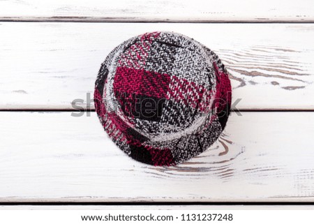 Flat lay checkered colourful hat. White wooden desks surface background.