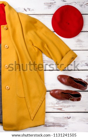 Pulled over yellow sleeve of a winter coat. Red womens hat and brown shoes.