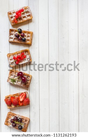 Homemade waffles with summer berries on a light table. Selective focus.