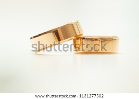 Gold wedding rings on a white table in bright light