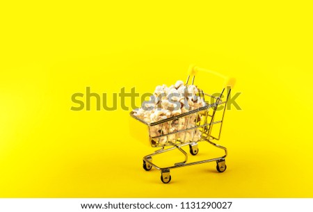 Popcorn in a shopping trolley on pink background top view