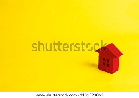 A small red wooden house stands on a yellow background. The concept of buying and selling real estate, renting. Search for a house. Affordable housing, credit and loans. Investments in business