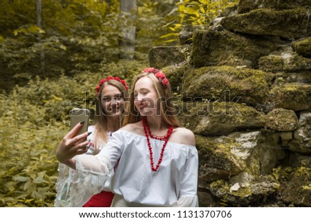 Two girls in Ukrainian folk costume make a selfphage smartphone.