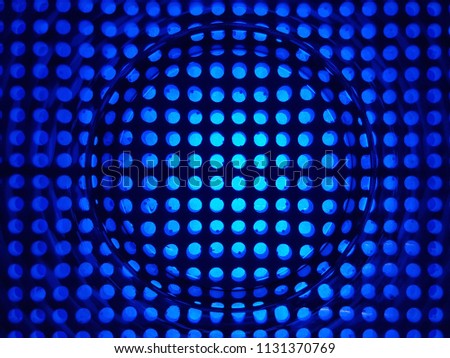 A blue lattice in a hole, a cage. A transparent circle, a glass in the center. Music, speaker art work. Blue background.