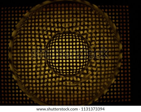 A yellow lattice in a hole, a cage. A transparent circle, a glass in the center. Music, speaker art work. Yellow background.