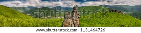 Panoramic landscape: a large rocky peak against the background of green mountains, hills and smaller rocks, a contrasting blue sky and clouds. HDR image with polarisation lens filter Royalty-Free Stock Photo #1131464726