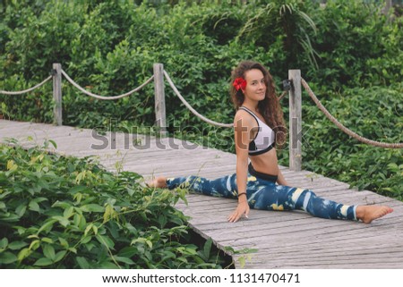 Young woman practicing splits outdoor with green background during yoga retreat in Bali