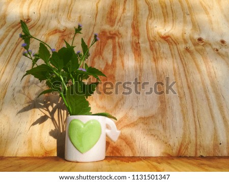 Flowers in a vase With a plank background And morning sunlight is a component in the picture.