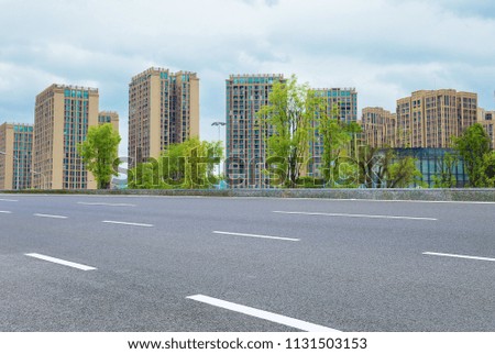 High-rise city center, clean asphalt road, lush park trees