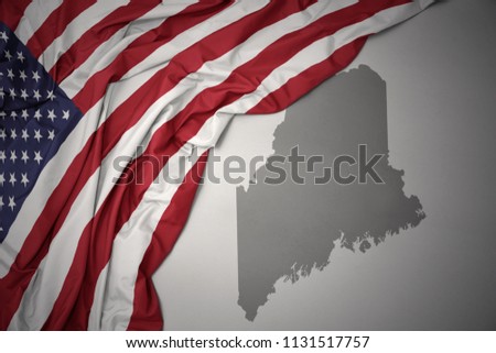 waving colorful national flag of united states of america on a gray maine state map background.