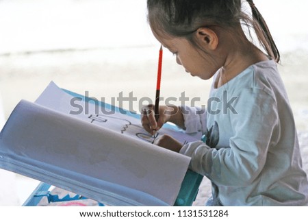 Little asian girl  drawing  with color pencils