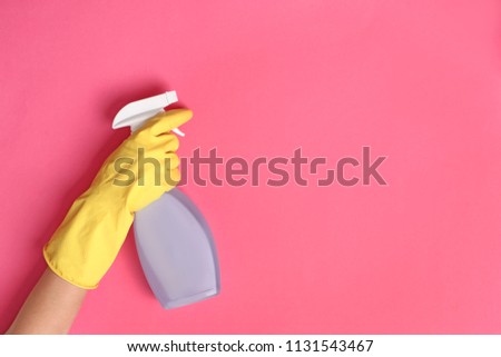 Woman holding bottle of cleaning product on color background