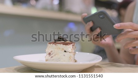 Woman taking photo on cake in cafe