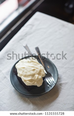 Dark chocolate cake with cream cheese on the table.