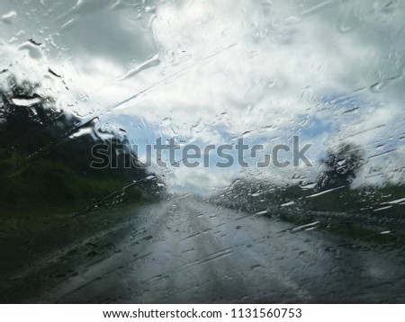 Road view through car windshield with rain drops, Driving in rain. 