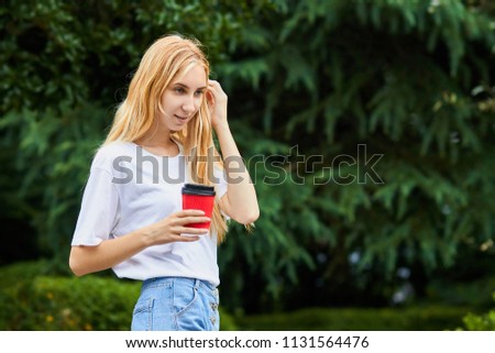 Young smiling woman holding the cup of coffee