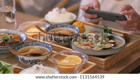 Woman taking photo on her dishes in Taiwanese restaurant 