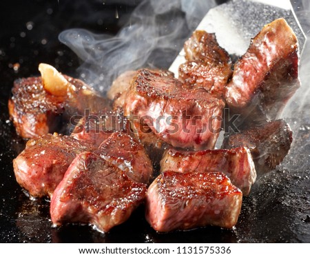 Cooking dice steak on iron hot plate Royalty-Free Stock Photo #1131575336