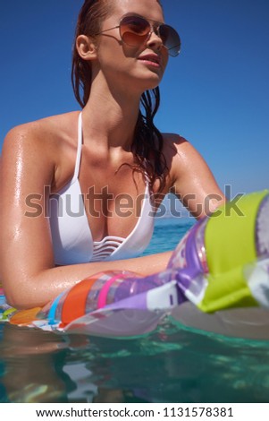 A beautiful young girl lies on a mattress in the open sea