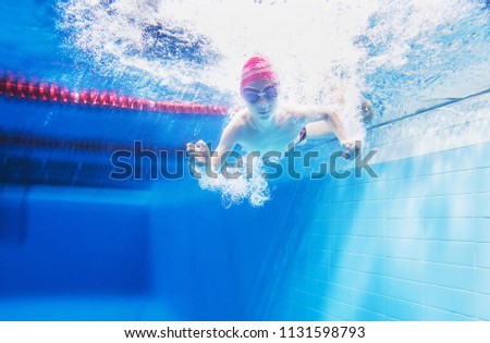 little boy having fun under water in the pool