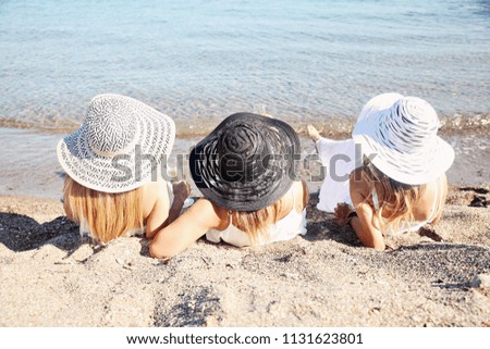 Three girls at the beach with their hats