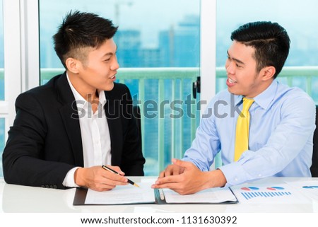 Asian man signing insurance or employment contract in office