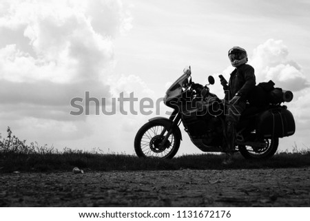 Biker man and tourist off road motorcycle with side bags, silhouette wallpaper concept, enduro advetnture, space for text, dark dramatic view, black and white, BW
