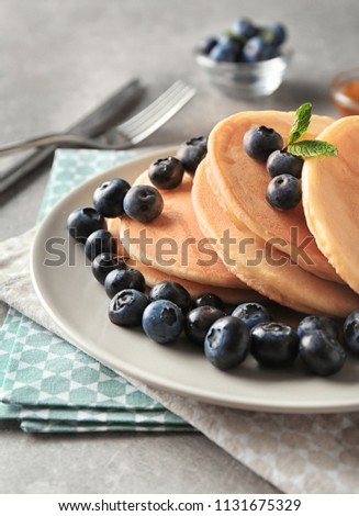 Plate with delicious pancakes and berries on light table, closeup