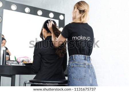 partial view of hairstylist doing hairstyle for businesswoman in suit
