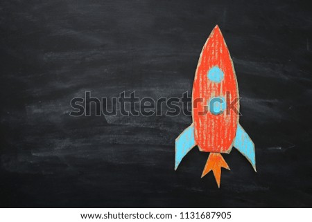 Rocket cut from cardboard and painted over chalkboard background