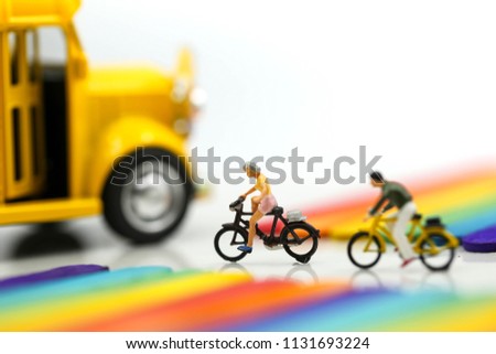 Miniature people : cycling of school bus  with Colorful ice cream sticks background.