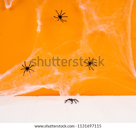 Empty rustic table in front of spider web background, orange background with bats and cobwebs, Halloween concept