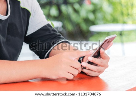 A man sitting in a park telephone on a red table.