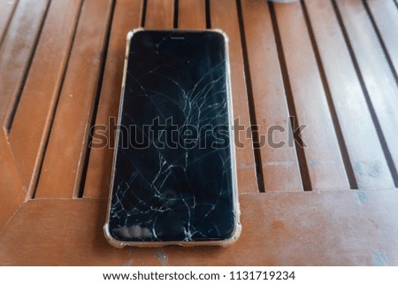 Smartphone with broken screen on table.