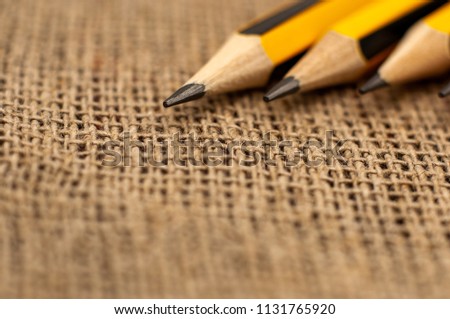 Graphite pencils and paper clips on the linen textile background. Macro. Shallow depth of field