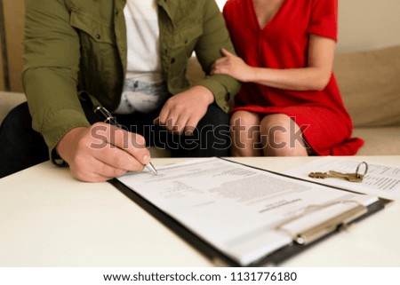 Young happy couple signing real estate purchase contract.