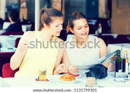 portrait of two happy american  female friends searching route on the map 
