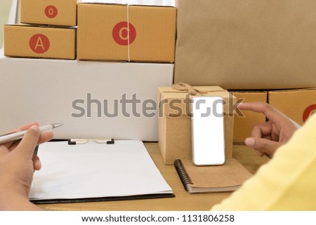 Businessman working with mobile phone and packing brown parcels box at home office. hands seller prepare product ready for deliver to customer. Online selling, e-commerce Start up shipping concept