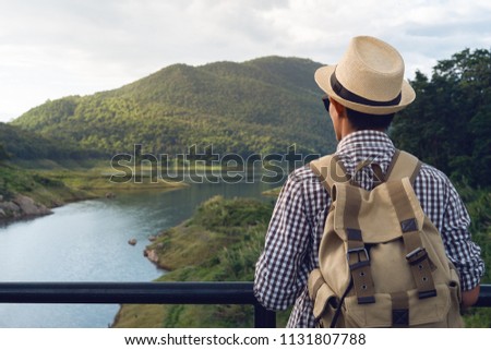 Young man backpacker travel standing on suspension rope bridge with nature mountain background.