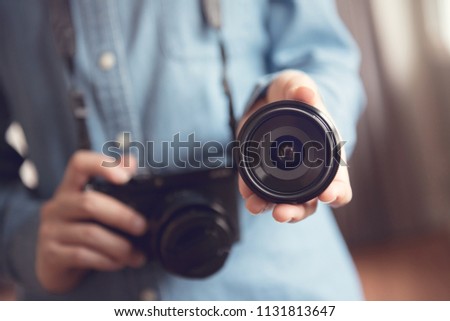 Photographer showing lens camera while hand using camera.