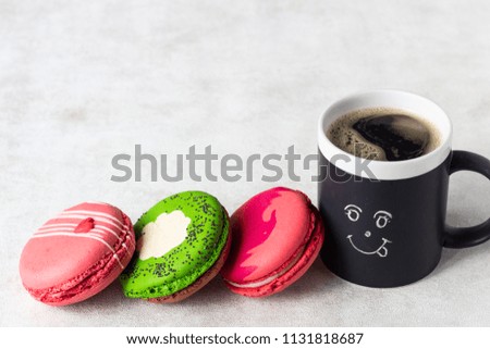 Colourful macarons with happy cup on light background. Romantic concept with copy space. Sweet dessert for coffee break. Concept about love and relationship