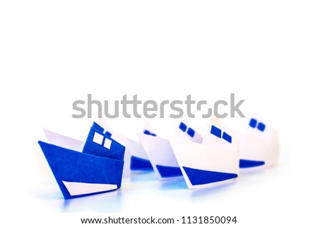 Leadership concept with blue paper ship leading among white.