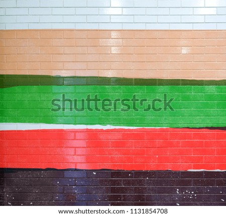 The brick wall is painted in bright colors. Detail of a painted tiled facade in vibrant colors.