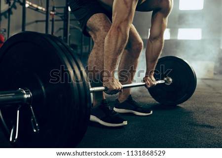 Fit young man lifting weight working out at a gym. Sport, fitness, weightlifting, bodybuilding, training, athlete, workout exercises concept Royalty-Free Stock Photo #1131868529