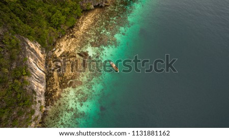 Aerial top view of a small boat in turquoise water near Maya Bay, Phi Phi Island, Thailand