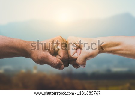 Man giving fist bump in sun rising nature background. power of teamwork concept. vintage tone Royalty-Free Stock Photo #1131885767