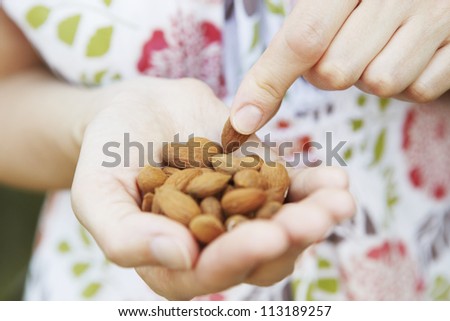 Close Up Of Woman Eating Handful Of Almonds Royalty-Free Stock Photo #113189257