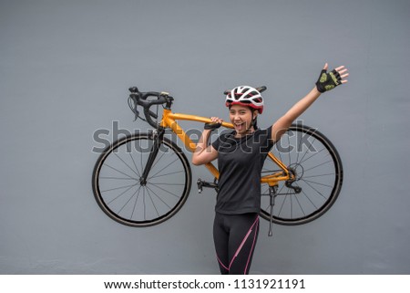 Young female cyclist in professional cycling clothing lifting bicycle .Active lifestyle concept.